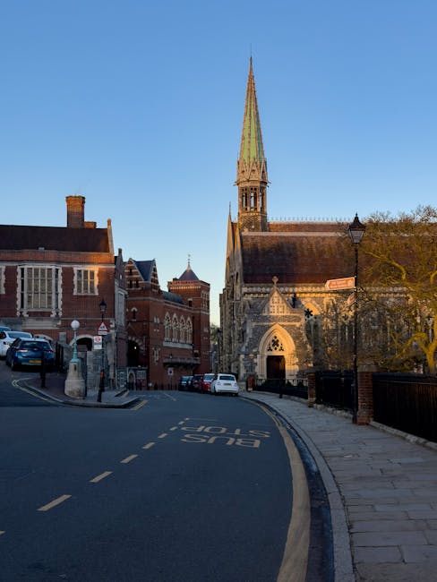An empty residential street in Wealdstone during sunset, with a slight incline and narrow roadway. On the left side, there are white multi-storey buildings with windows and small railings, indicating
